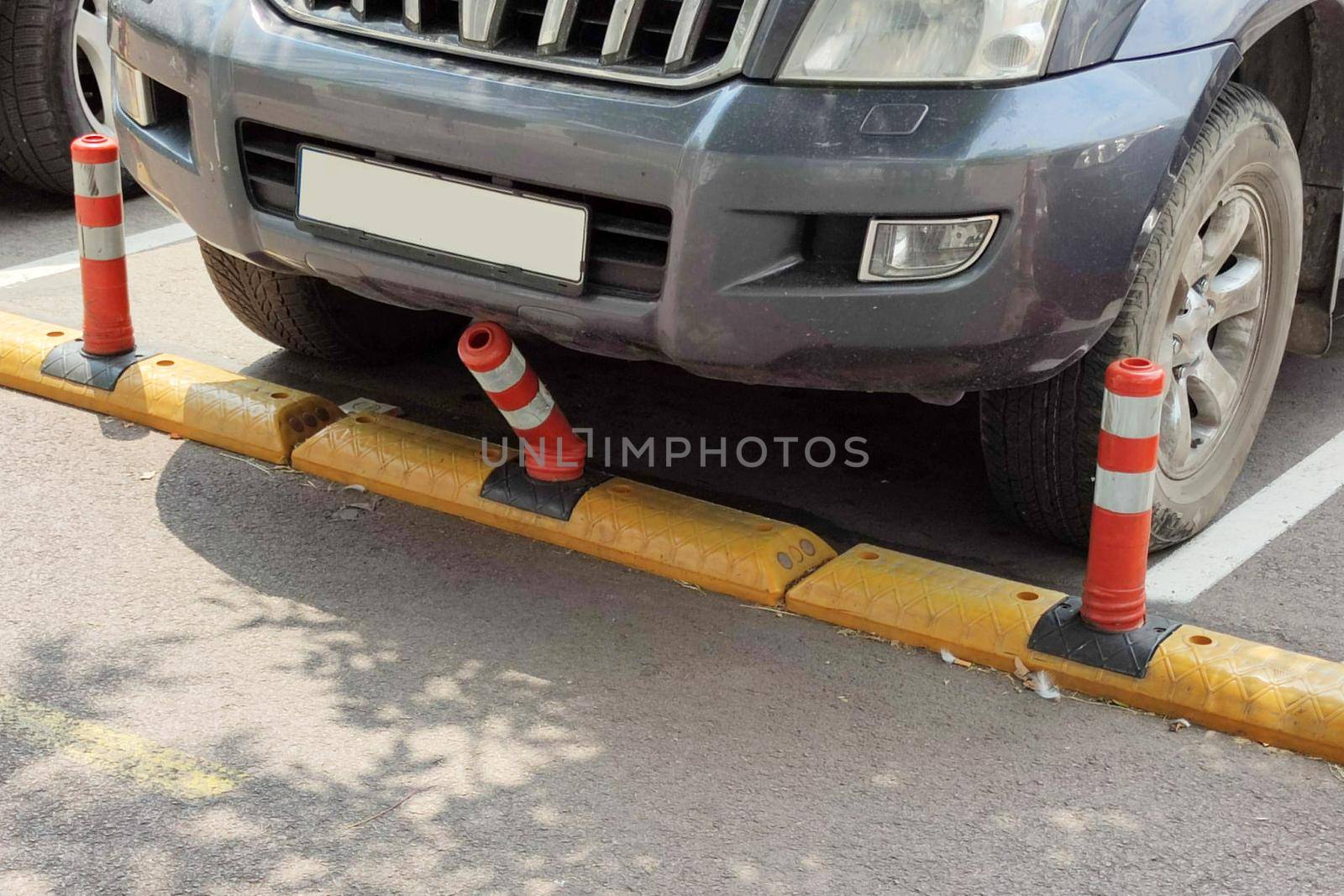 the car bent the bumper of the plastic road barrier in the parking lot.