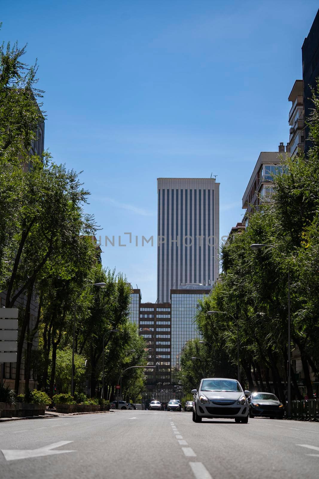 Sunny day in Madrid city downtown with business buildings and cars in the background. Road street shot by papatonic
