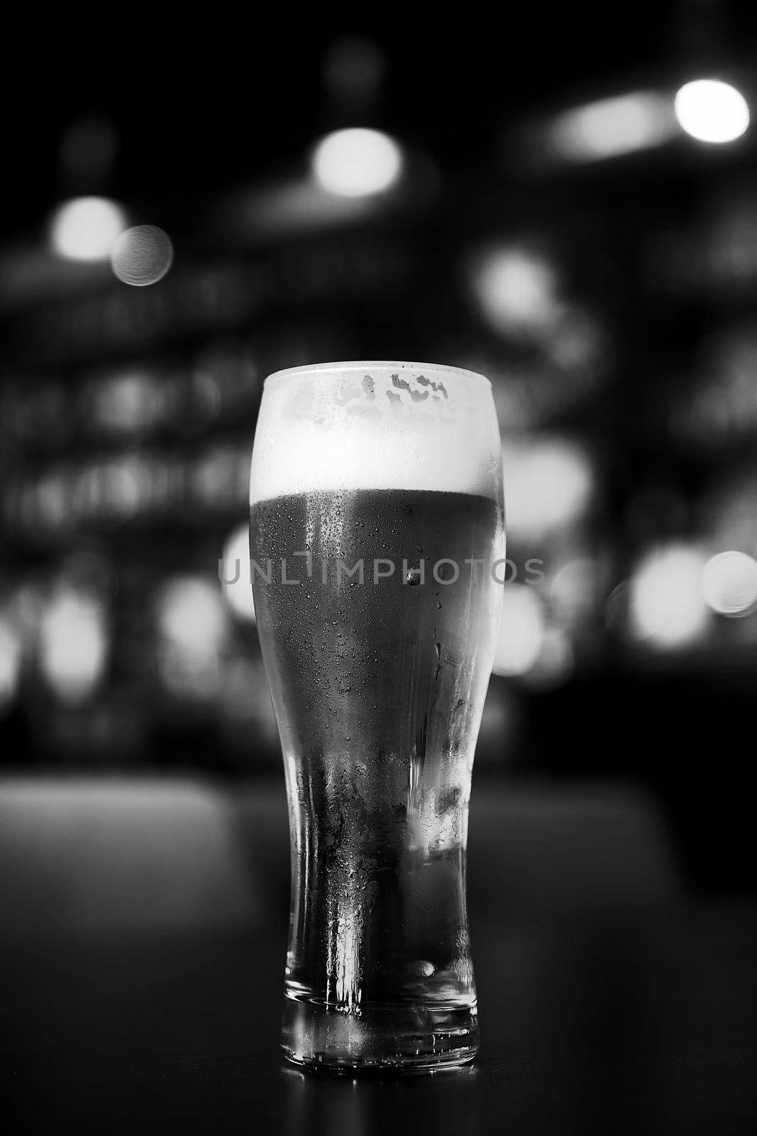 Glass of beer on a table in a bar on blurred bokeh background.