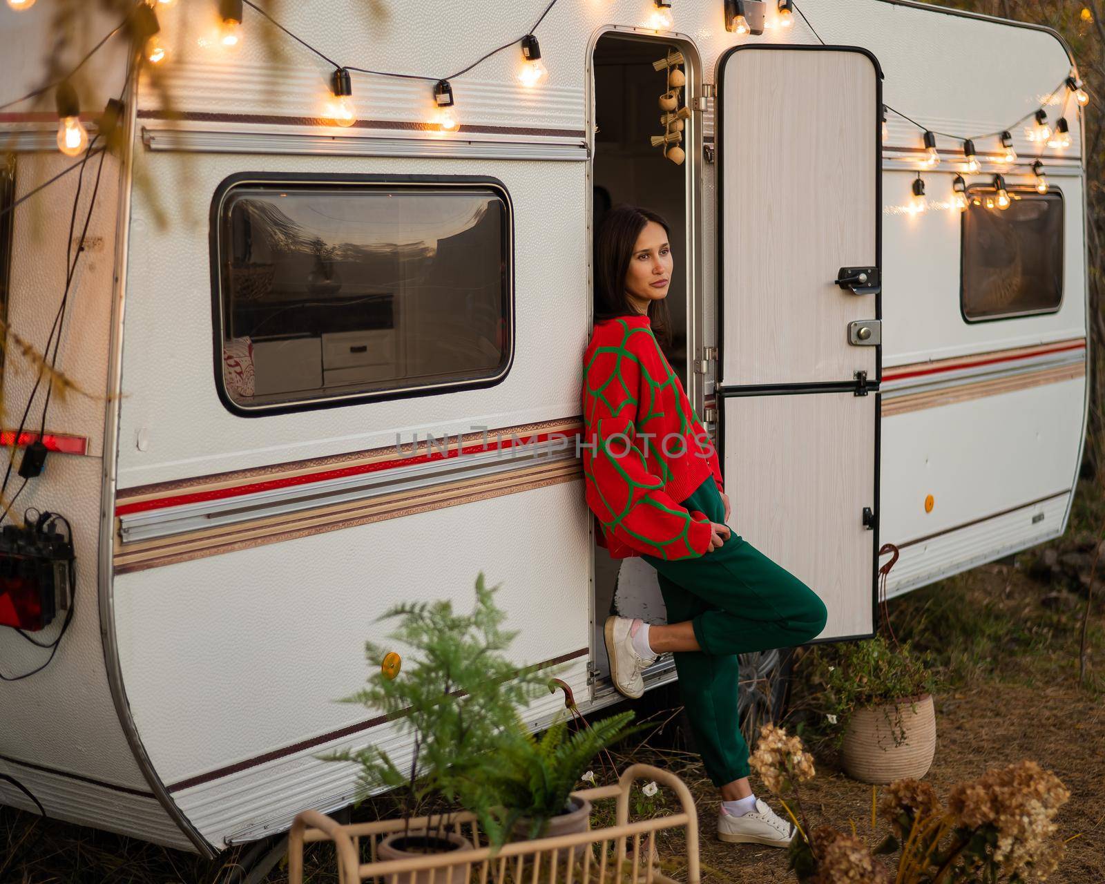 Caucasian woman in oversized red knitted jumper travels in motorhome in autumn