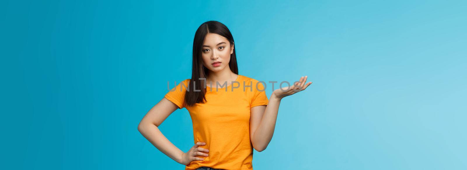 Ignorant bossy asian woman high-standarts, look dismay arrogant, act snobbish complaining bad service, raise hand full disbelief, cannot stand nonsense, stand annoyed blue background.