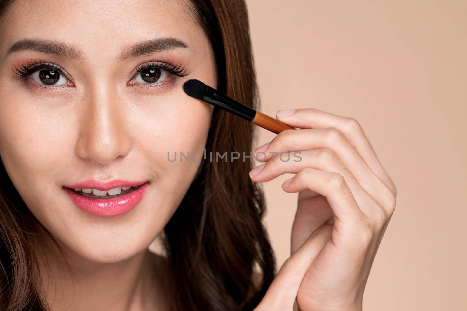 Closeup ardent young woman with healthy fair skin applying her eyeshadow with brush. Female model with fashion makeup. Beauty and makeup concept.