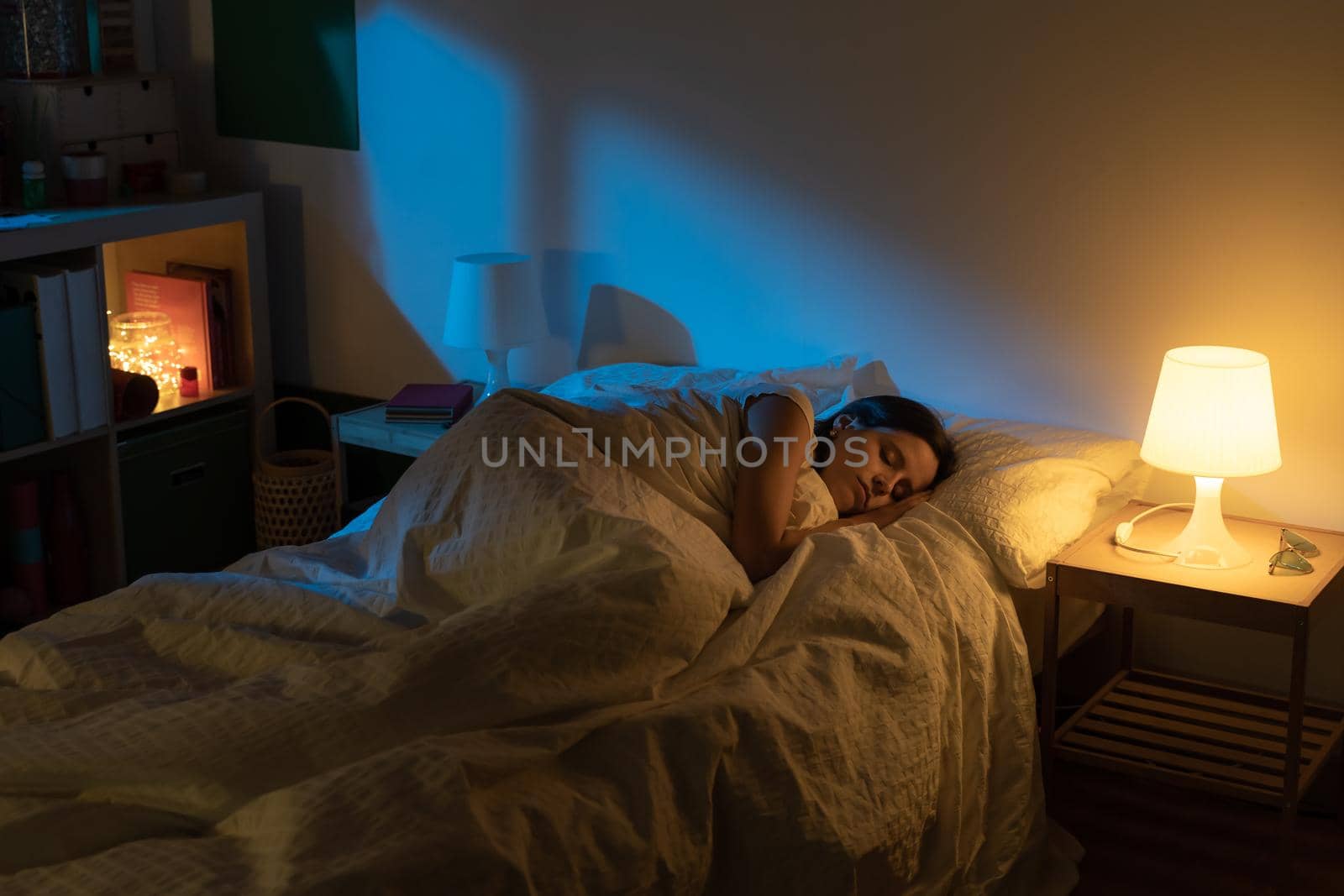 Beautiful girl suffering from insomnia lying in her bed with Blue Colors from the moon. High quality photo