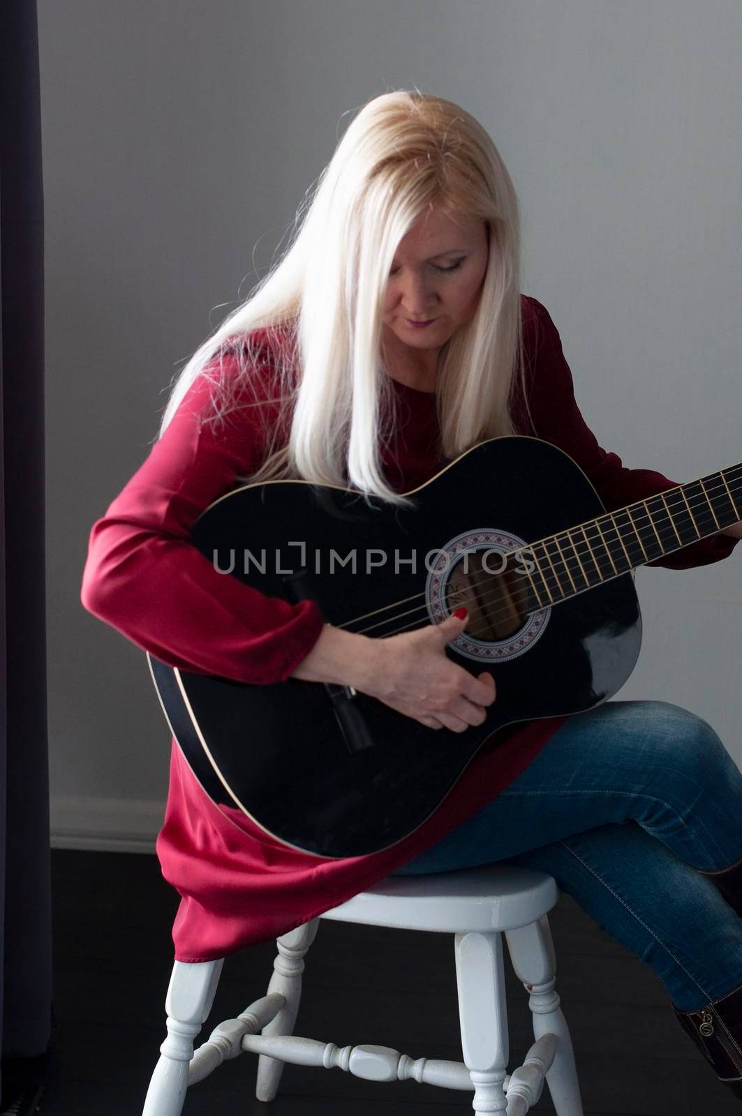 beautiful young blonde woman in a red dress with a black guitar, favorite hobby by KaterinaDalemans