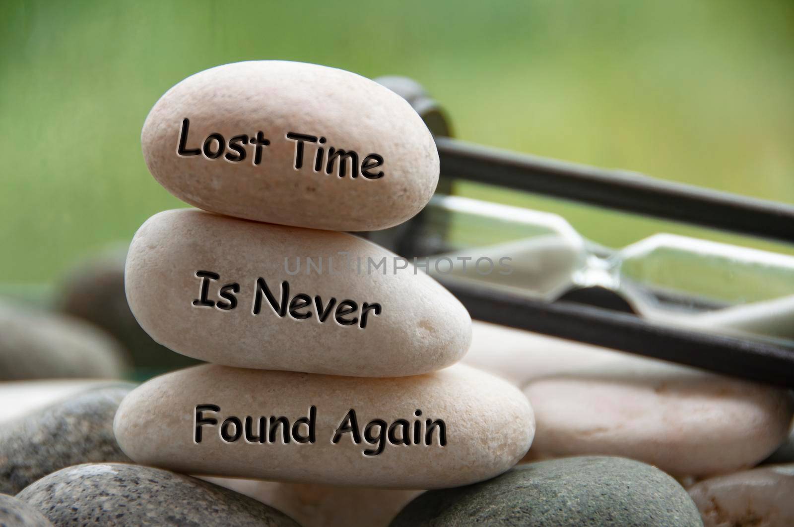 Lost time is never found again text engraved on stones with minute glass background. Copy space and time concept by yom98