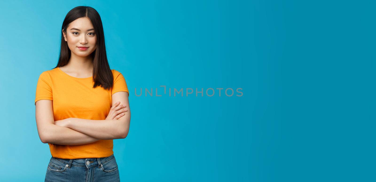 Confident motivated feminine asian woman feel empowered deal office problems manage business, hold hands crossed chest, smiling determined, wear yellow t-shirt, stand blue background.