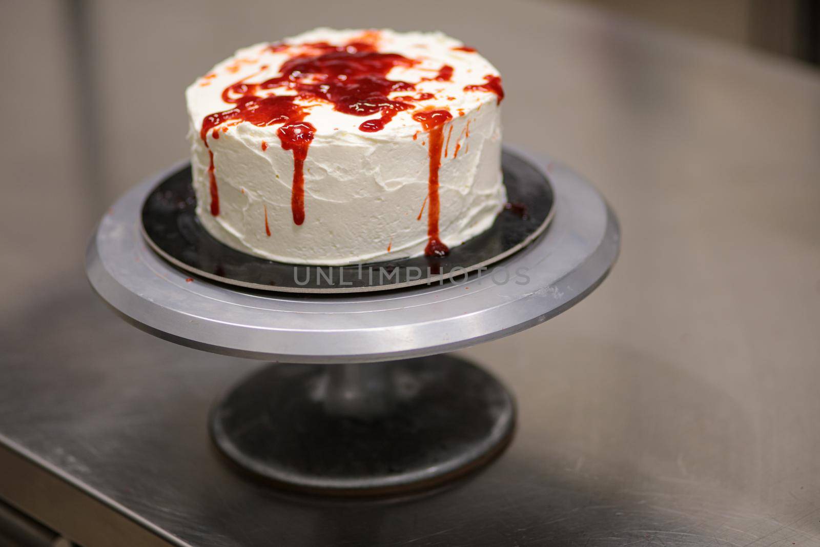 designer chef decorating white red bloody horror crime cake for halloween party by verbano