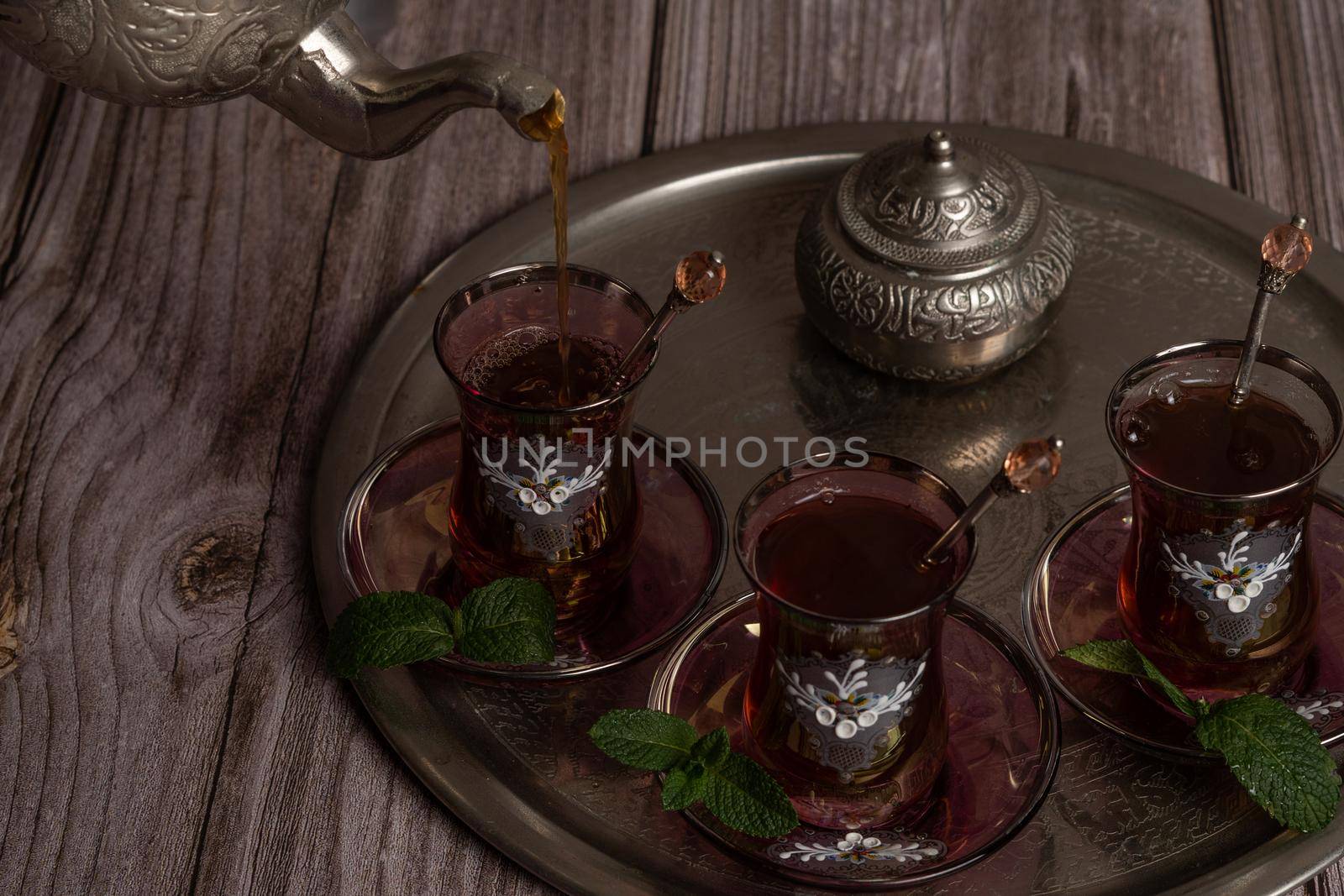 serving hot Moorish tea on a tray with glasses and pitcher on a wooden table