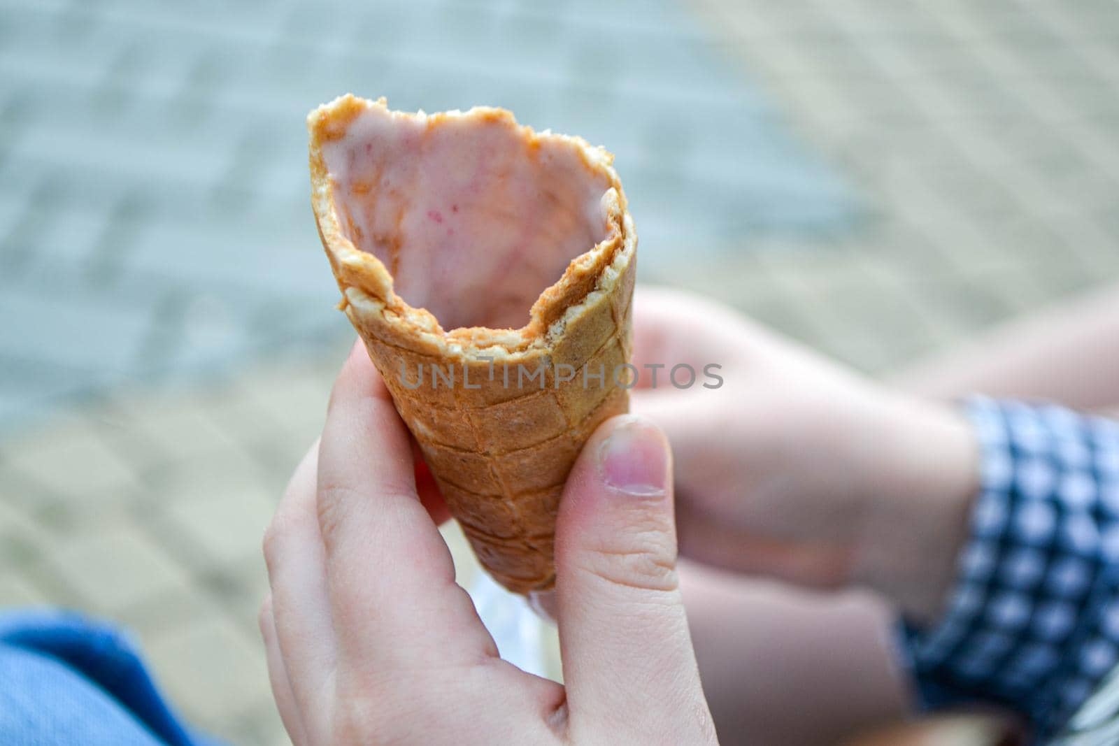 Ice cream cone in hand pastel gray background. . Concept of eating ice cream. A man holds a waffle without ice cream in his hand on a different light background. High quality photo