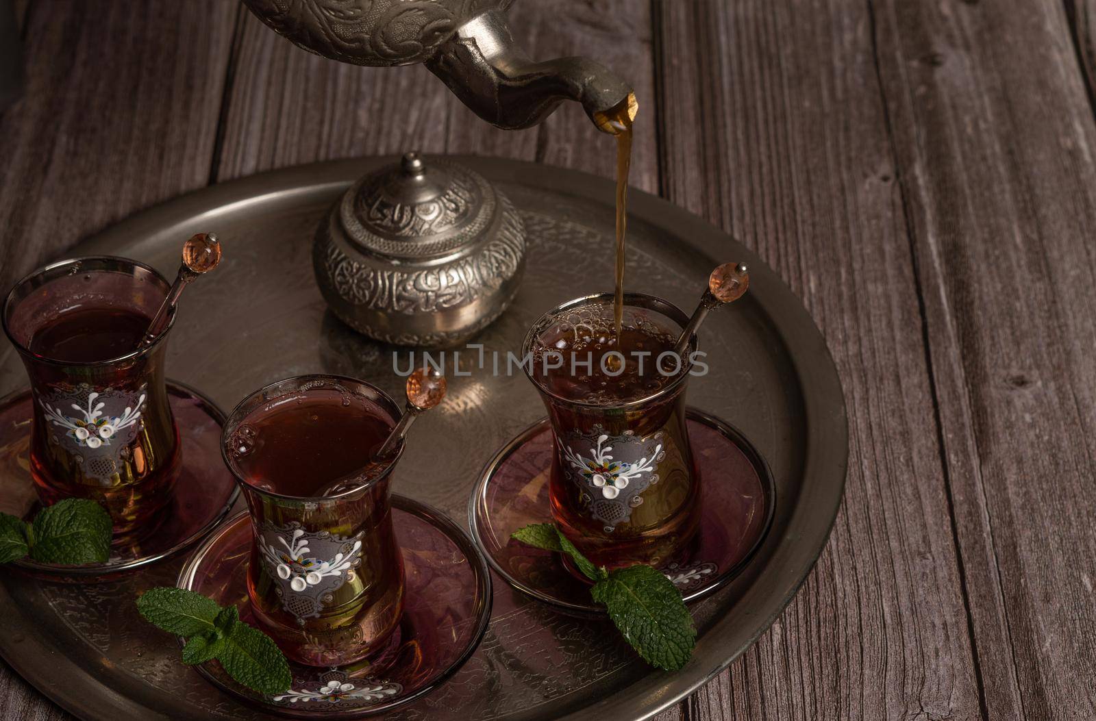 serving hot Moorish tea on a tray with glasses and pitcher on a wooden table