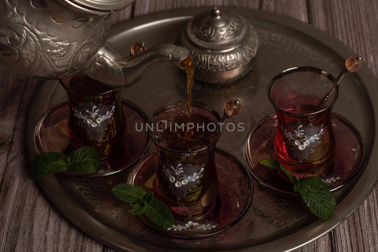 serving hot Moorish tea on a tray with glasses and pitcher on a wooden table