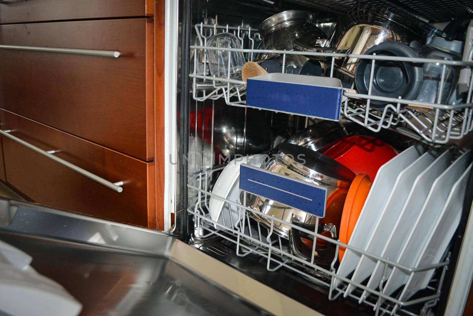 Transparent and black and white dishes as well as cutlery and glasses are washed in the dishwasher, inside view, drops and splashes of water. High quality photo