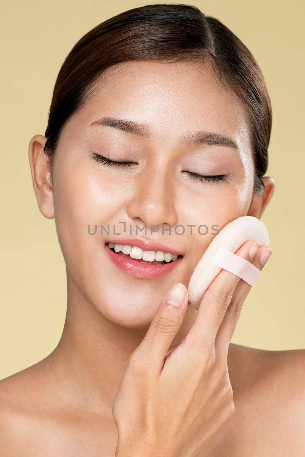 Closeup ardent woman applying her cheek with dry powder and looking at camera. Portrait of younger with perfect makeup and healthy skin concept.