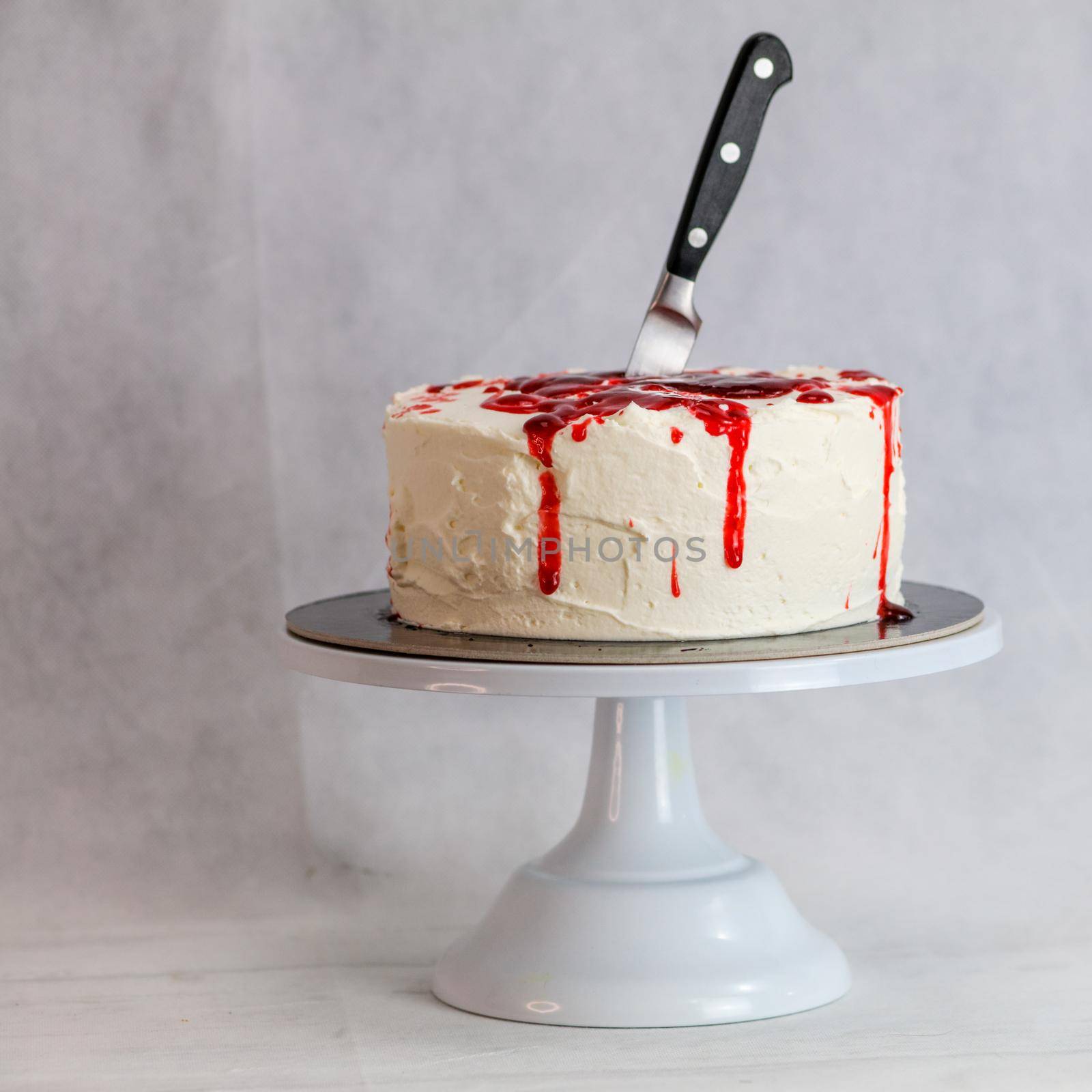 designer chef decorating white red bloody horror crime cake for halloween party by verbano