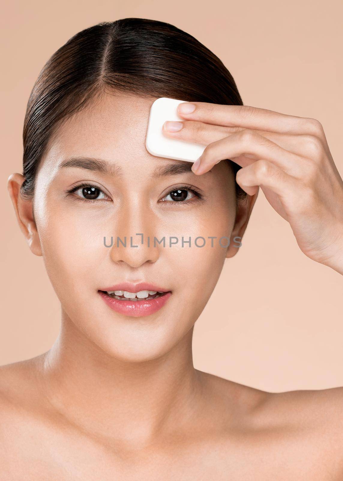 Closeup ardent woman applying her cheek with dry powder and looking at camera. Portrait of younger with perfect makeup and healthy skin concept.