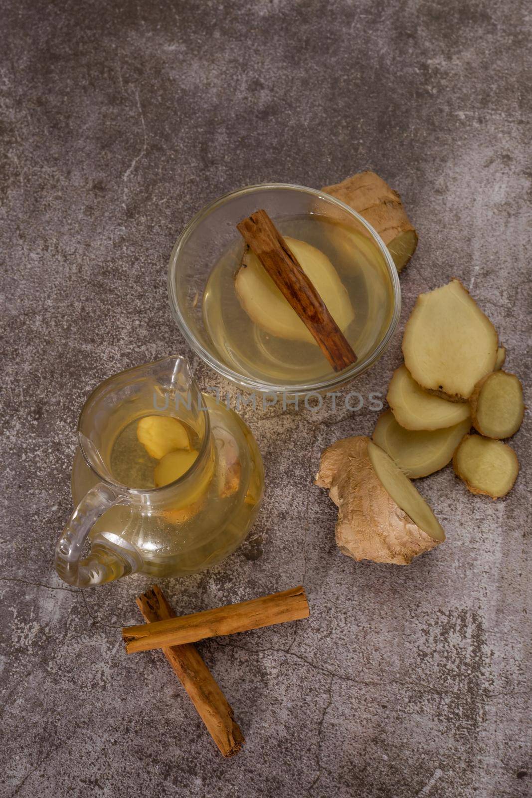 preparation of a ginger and cinnamon infusion with fresh produce natural roots and cinnamon stick served in a pitcher and a cup