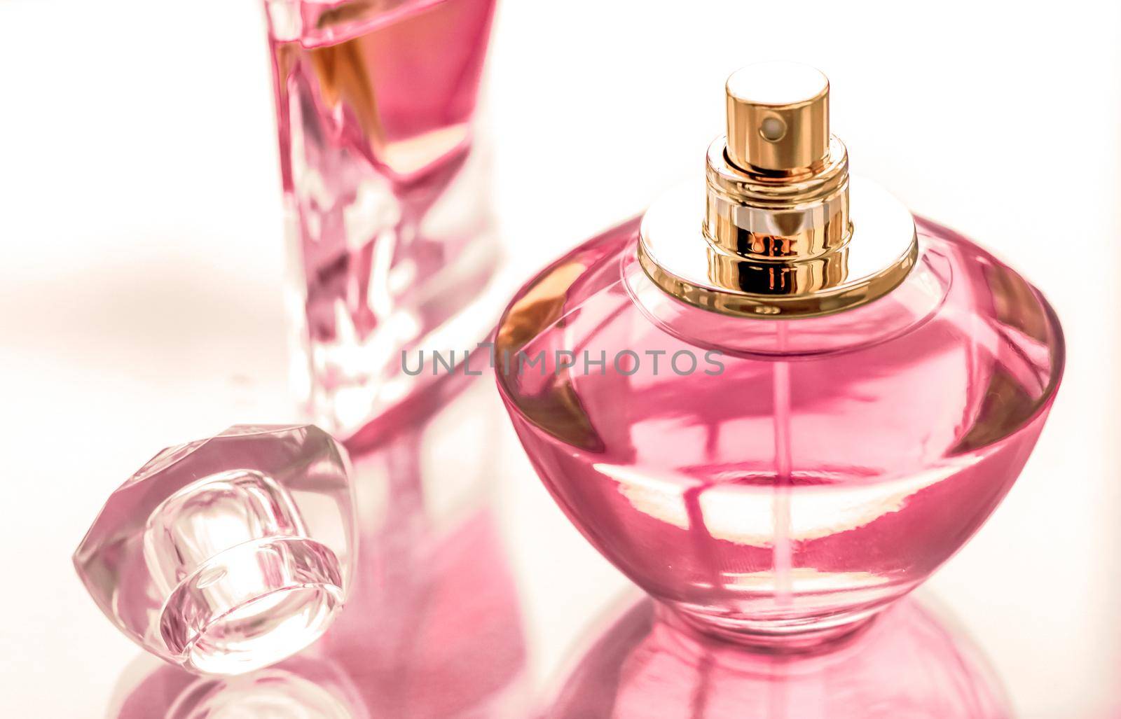 Perfumery, spa and branding concept - Pink perfume bottle on glossy background, sweet floral scent, glamour fragrance and eau de parfum as holiday gift and luxury beauty cosmetics brand design