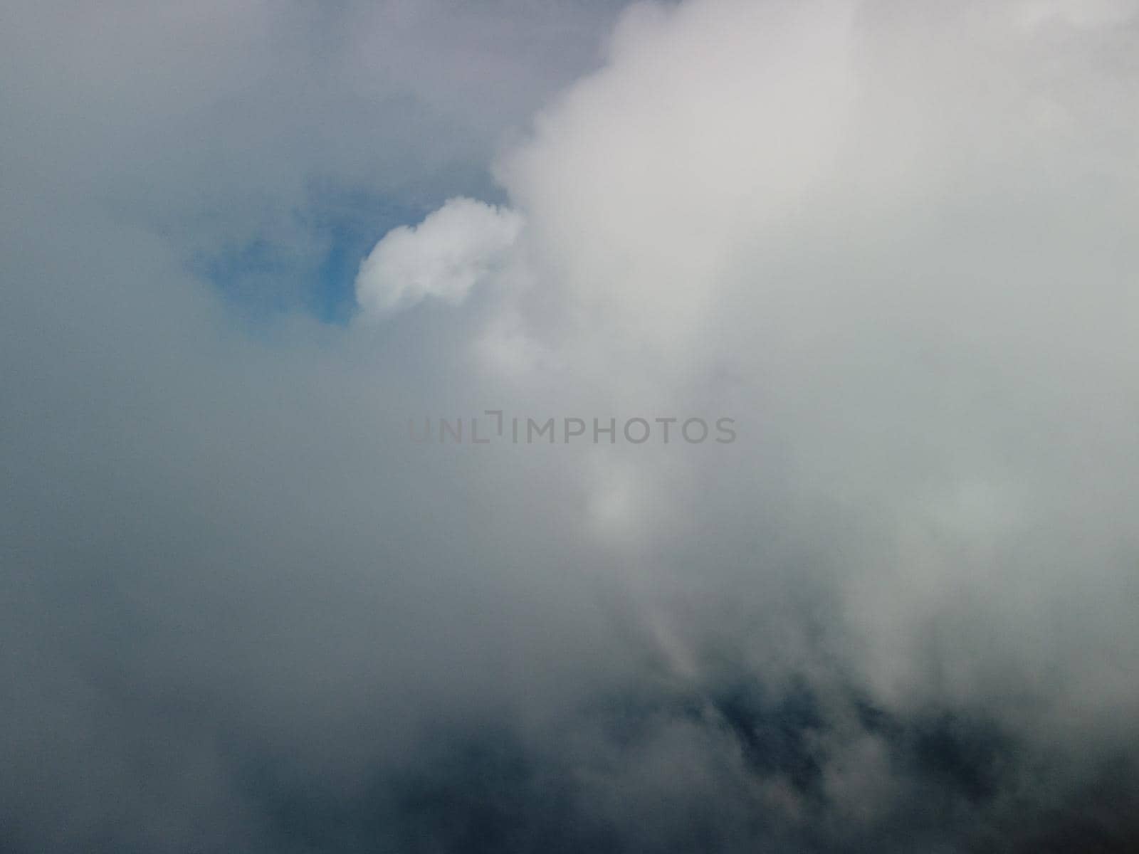 Aerial view drone flying above white clouds dense fog move quickly. Drone flies high back in blue sky through fluffy clouds. Beautiful foggy and cloudy slow moving Aerial view. Fog sea.