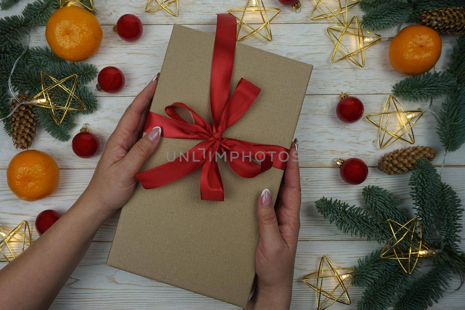 A woman's hand holds a gift in a craft package with a red satin bow. High quality photo