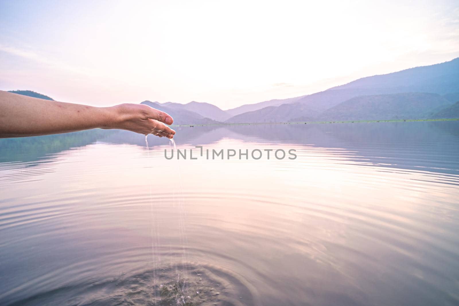 Woman taking clear water by hands on nature lake mountain background