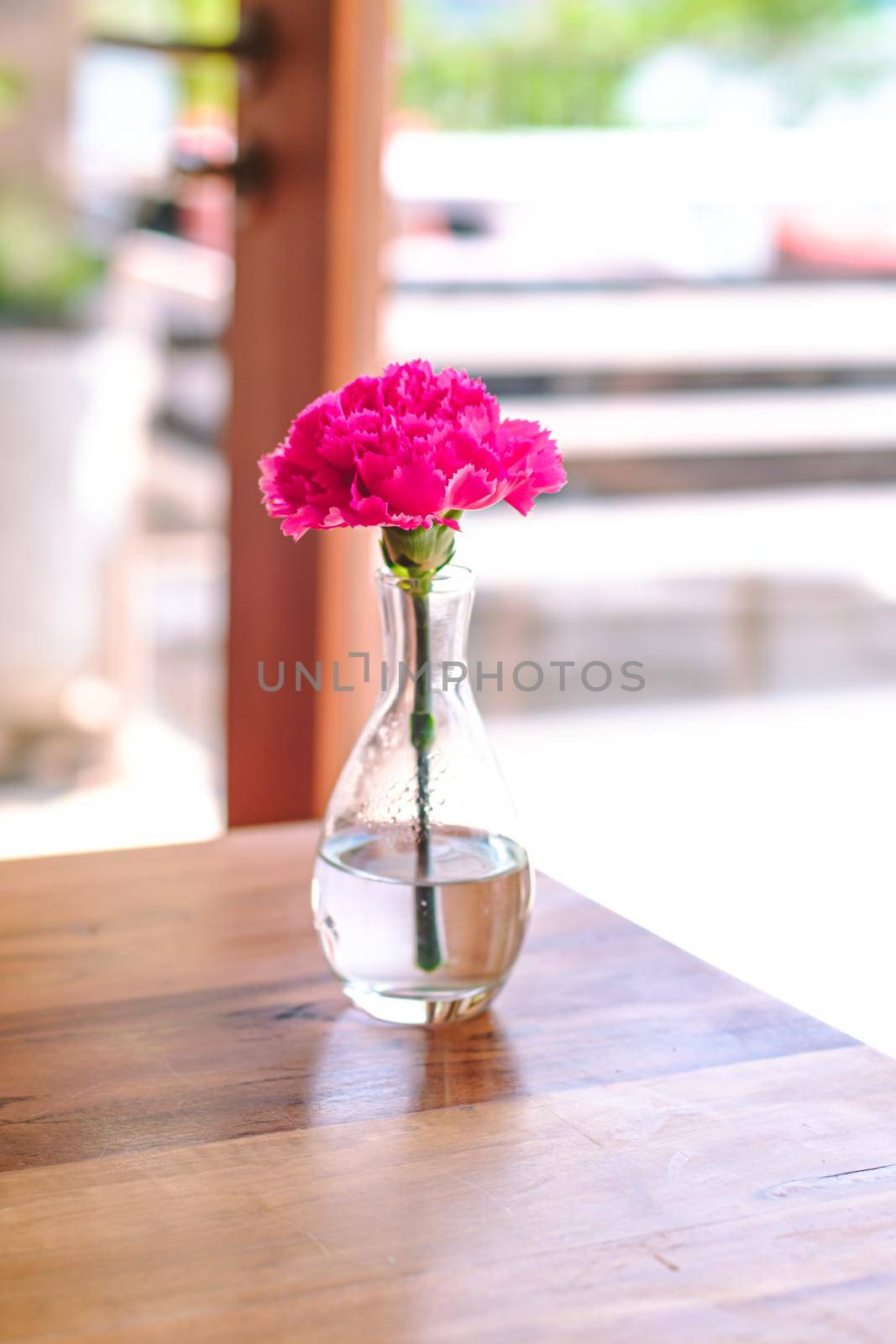 bouquet of Pink flowers in glass bottle on wooden table