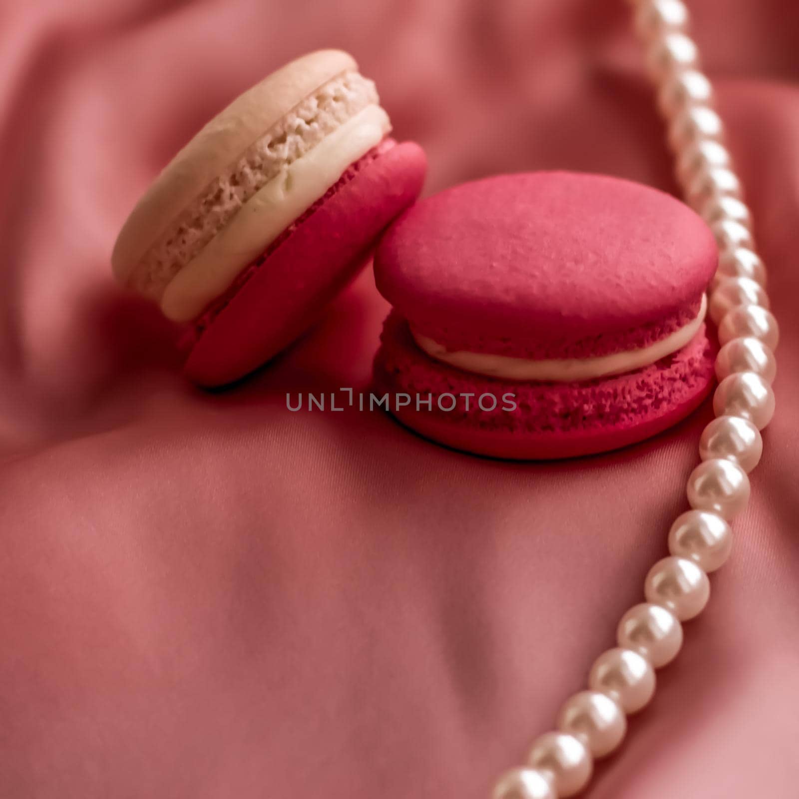 Girly, bakery and branding concept - Sweet macaroons and pearls jewellery on silk background, parisian chic jewelry, French dessert food and cake macaron for luxury confectionery brand, holiday gift