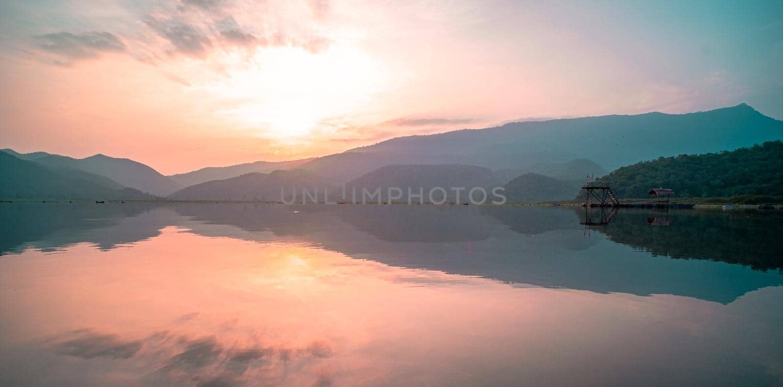 Panorama scenic of mountain lake with perfect reflection at sunrise. beautiful mountain range landscape with pink pastel sky with hills on background and reflected in water. Nature lake landscape by Petrichor