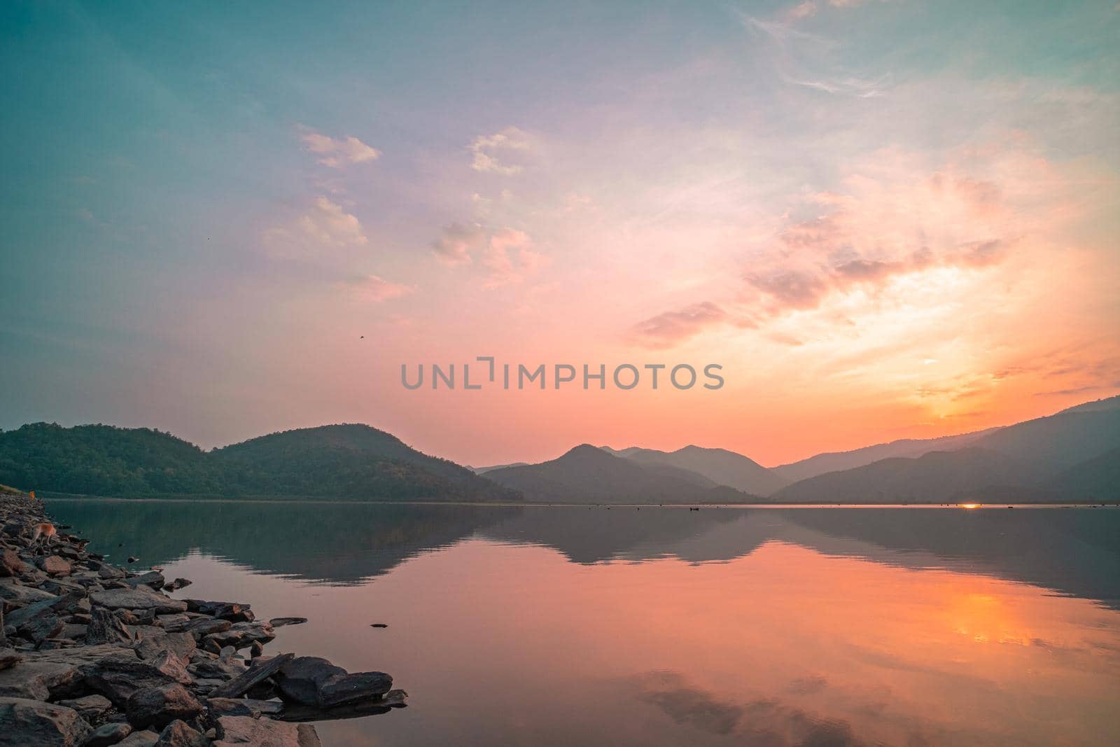 Panorama scenic of mountain lake with perfect reflection at sunrise. beautiful mountain range landscape with pink pastel sky with hills on background and reflected in water. Nature lake landscape