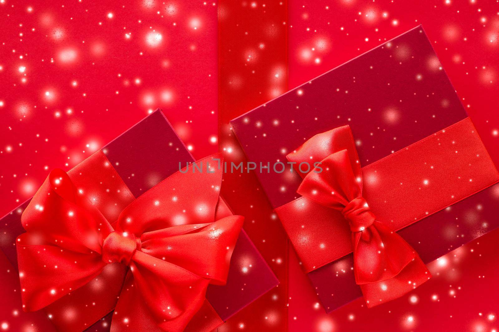 New Years Eve celebration, wrapped luxury boxes and Valentines Day card concept - Winter holiday gifts and glowing snow on red background, Christmas presents surprise