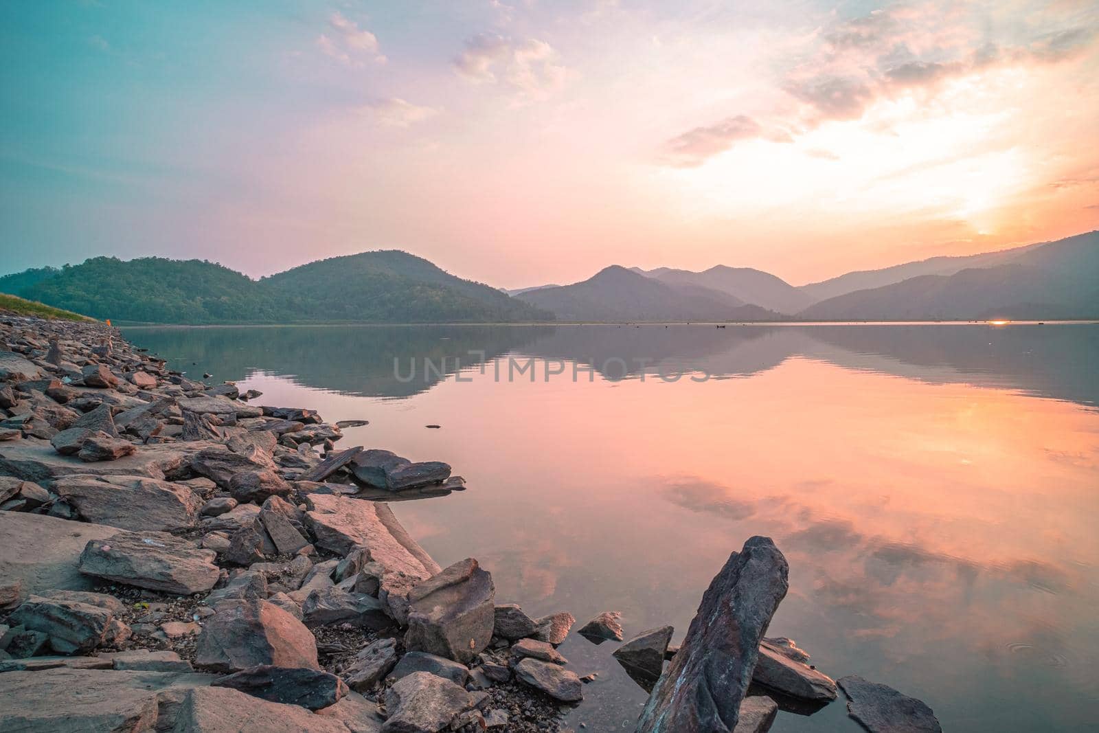 Panorama scenic of mountain lake with perfect reflection at sunrise. beautiful mountain range landscape with pink pastel sky with hills on background and reflected in water. Nature lake landscape