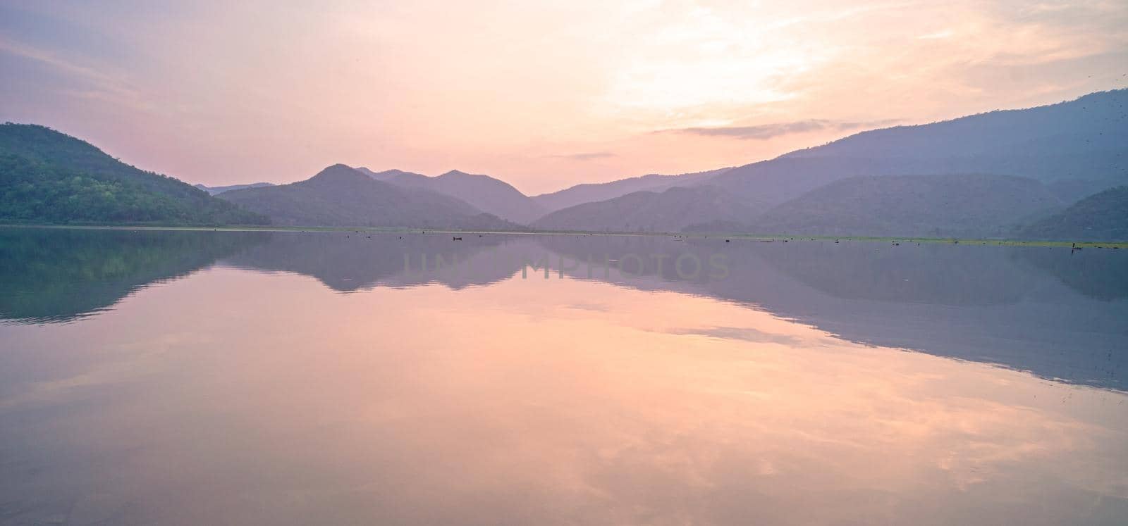 Panorama scenic of mountain lake with perfect reflection at sunrise. beautiful mountain range landscape with pink pastel sky with hills on background and reflected in water. Nature lake landscape by Petrichor