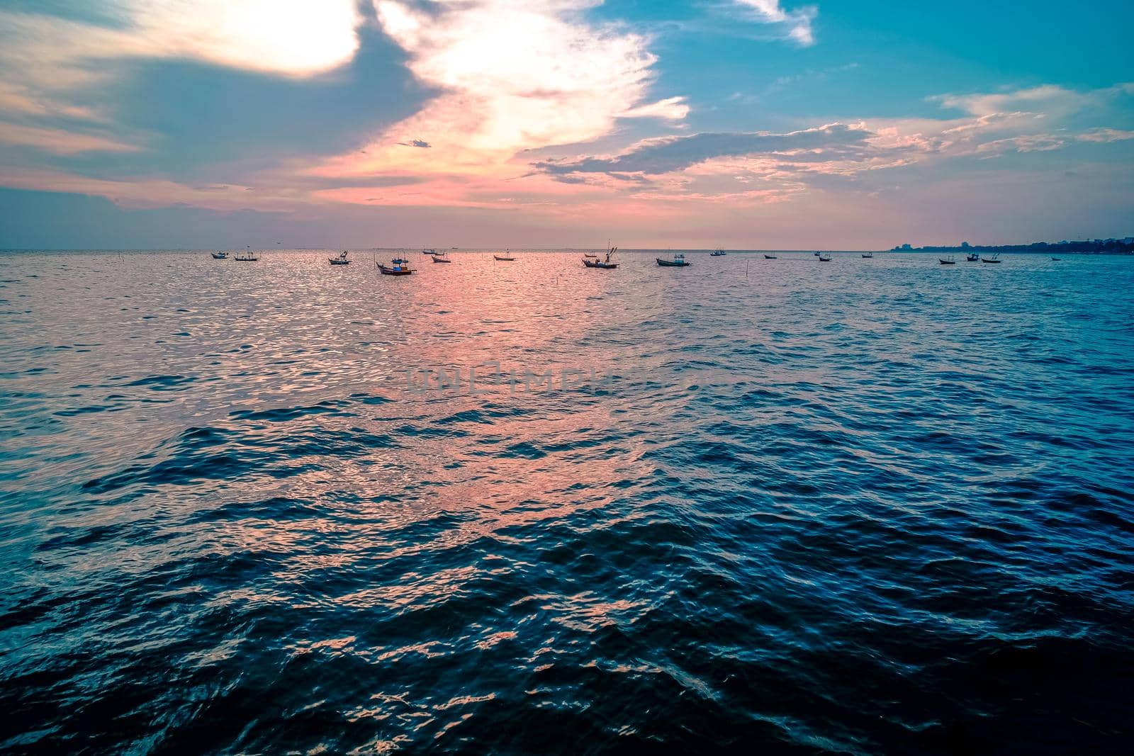 Beautiful sunrise on sea background with tropical wooden fishing boat