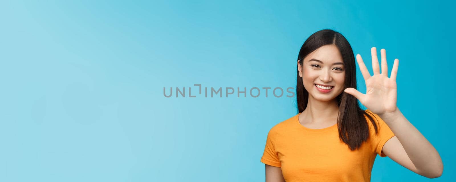Close-up good-looking friendly cheerful asian woman raise palm show number five, fifth, smiling joyfully, describe how many things need, stand blue background upbeat, communicate. Copy space