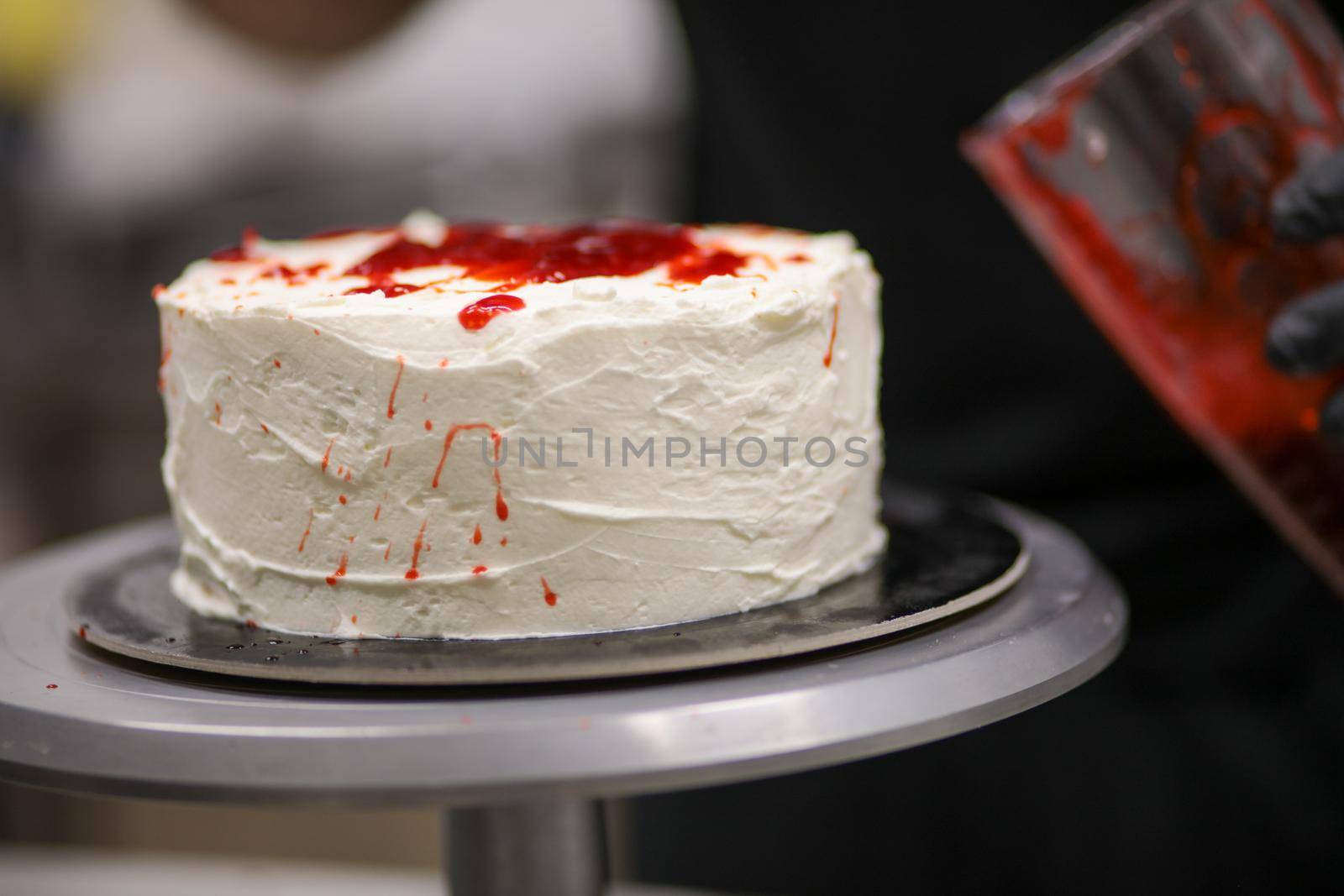 designer chef decorating white red bloody horror crime cake for halloween party by verbano