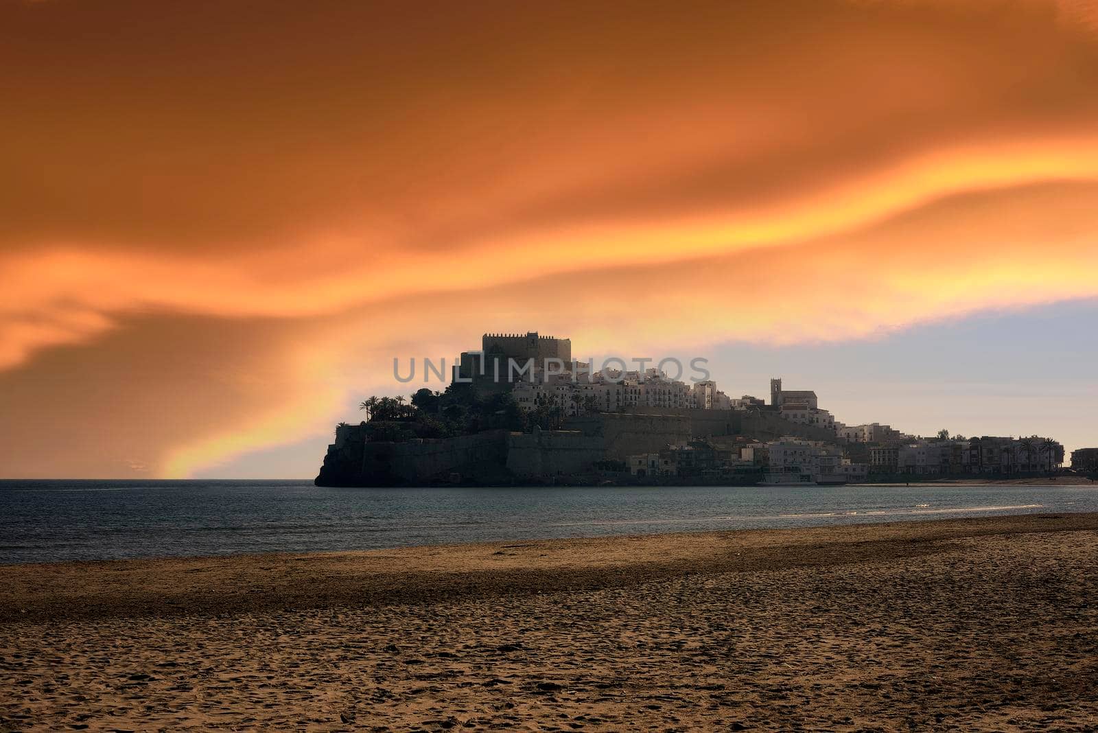 Peniscola , Valencian Community, Spain, view from the castle beach. Sunset or sunrise with orange clouds, deserted beach