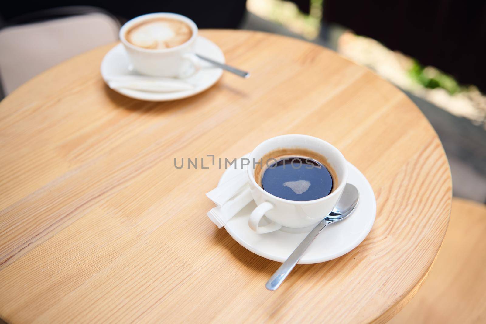 Top view cup of coffee americano and cappuccino on a wooden table, in the summer terrace of a cafeteria. Food and drink by artgf