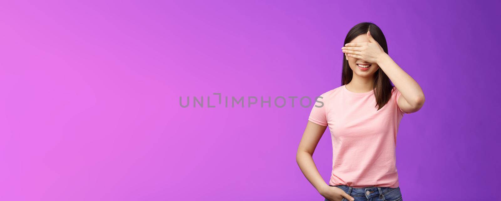 Cute tender stylish asian woman brunette smiling joyfully, anticipating gift, close eyes, cover face palm, awaiting present, cannot wait see what boyfriend prepared, stand purple background.