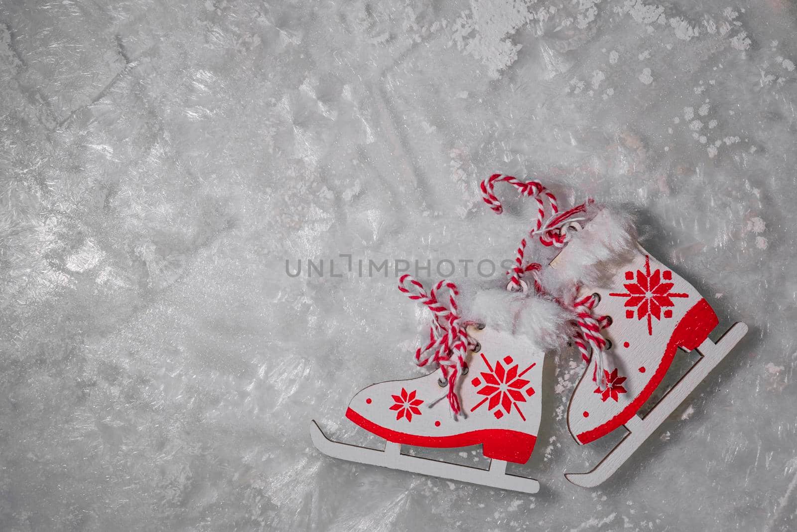 figurines of skates with a red pattern on frosty ice, sparkling frost or water crystals. winter sport or entertainment concept by Leoschka