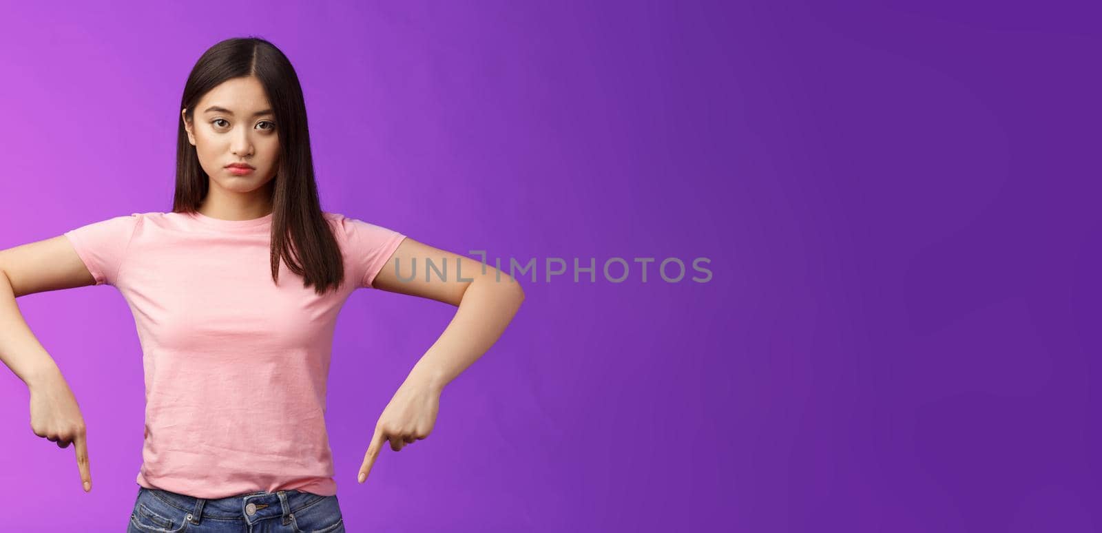 Serious-looking upset insecure asian female fighting stop cruel animal behaviour, pointing fingers down disappointed, look camera sincere fed up, standing depressed unsatisfied, purple background.