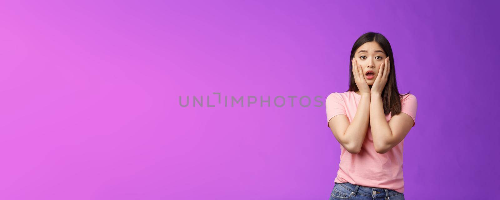 Concerned shocked timid insecure asian woman, feel pitty, shame hearing shocking news, grab face sorry for friend, gasping, opened mouth upset, sighing distressed, stand purple background by Benzoix