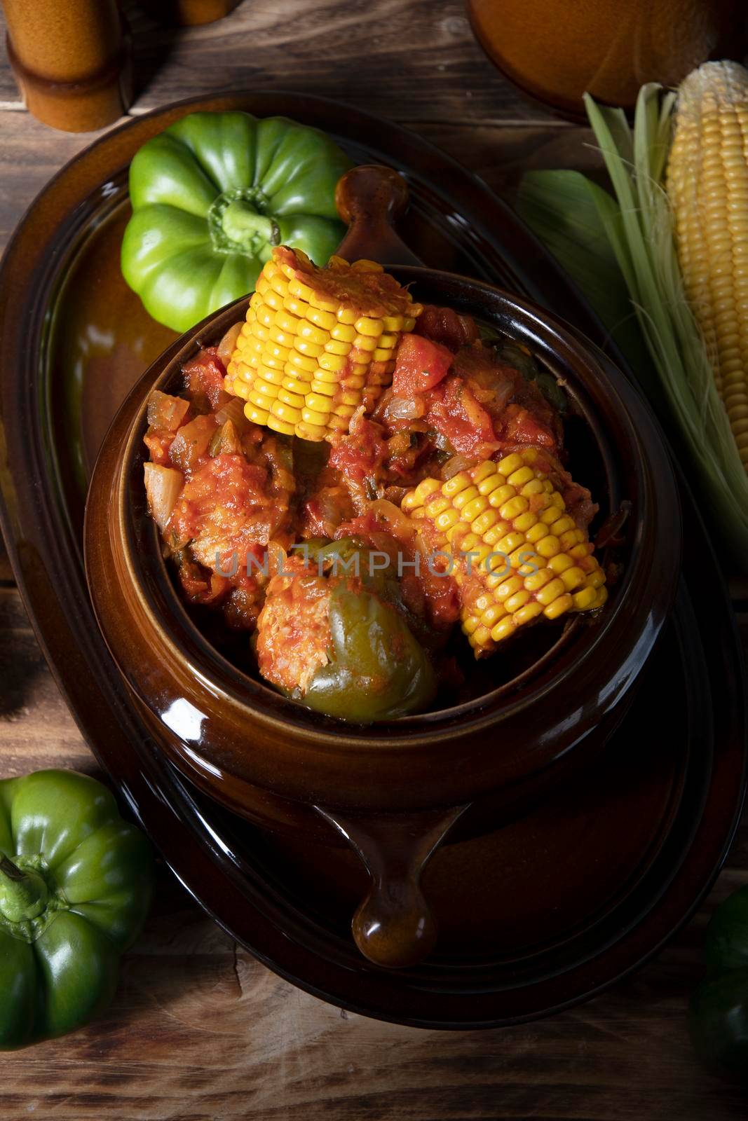 stuffed bell peppers with corn on the cob stewed in tomatoes, still life on wooden boards, traditional autumn dishes. High quality photo