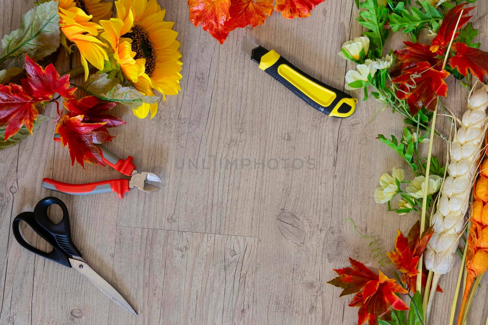 top view of sunflowers, autumn leaves, spikelets, scissors, stationery knife and other tools to create autumn decor. DIY by Leoschka