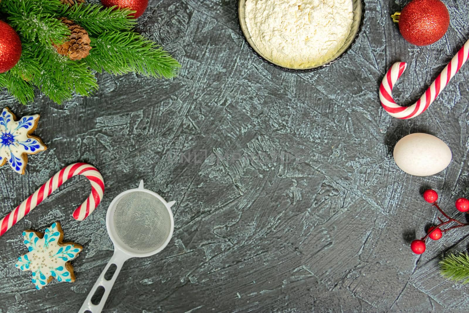 top view of table with flour, egg, strainer, sugar sticks and christmas holidays and fir tree. new year or christmas background. copy space