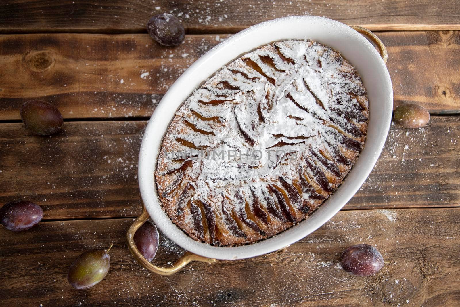ready plum cake sprinkled with powdered sugar on a wooden table sweet seasonal dessert, High quality photo