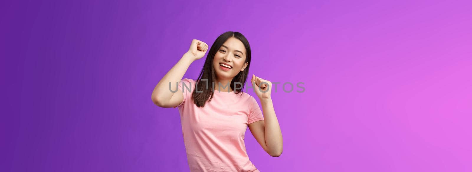 Joyful glamour asian attractive girl having fun enjoy awesome party feeling carefree, fist pump during dance, smiling broadly like good music, attend concert, stand purple background. Copy space