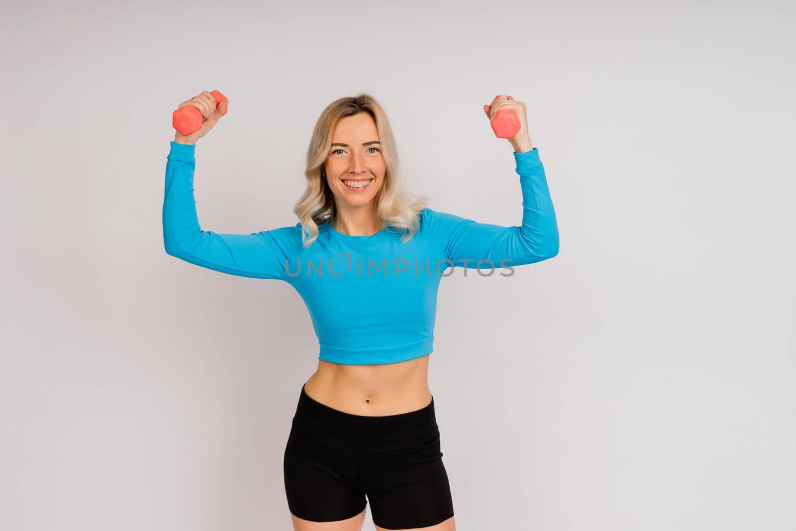 Sporty girl doing exercise with dumbbells, silhouette studio shot over a dark and white background