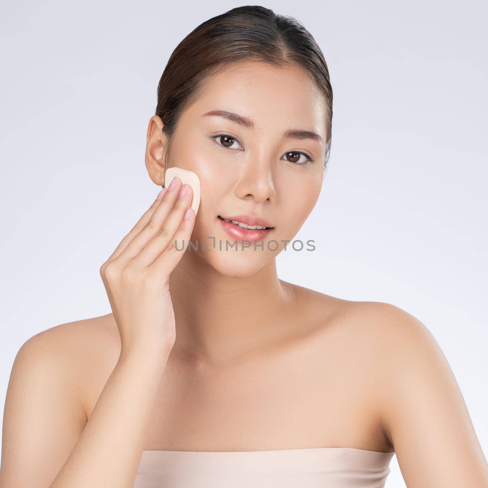 Gorgeous woman applying her cheek with dry powder. Beauty care, cosmetic concept by biancoblue