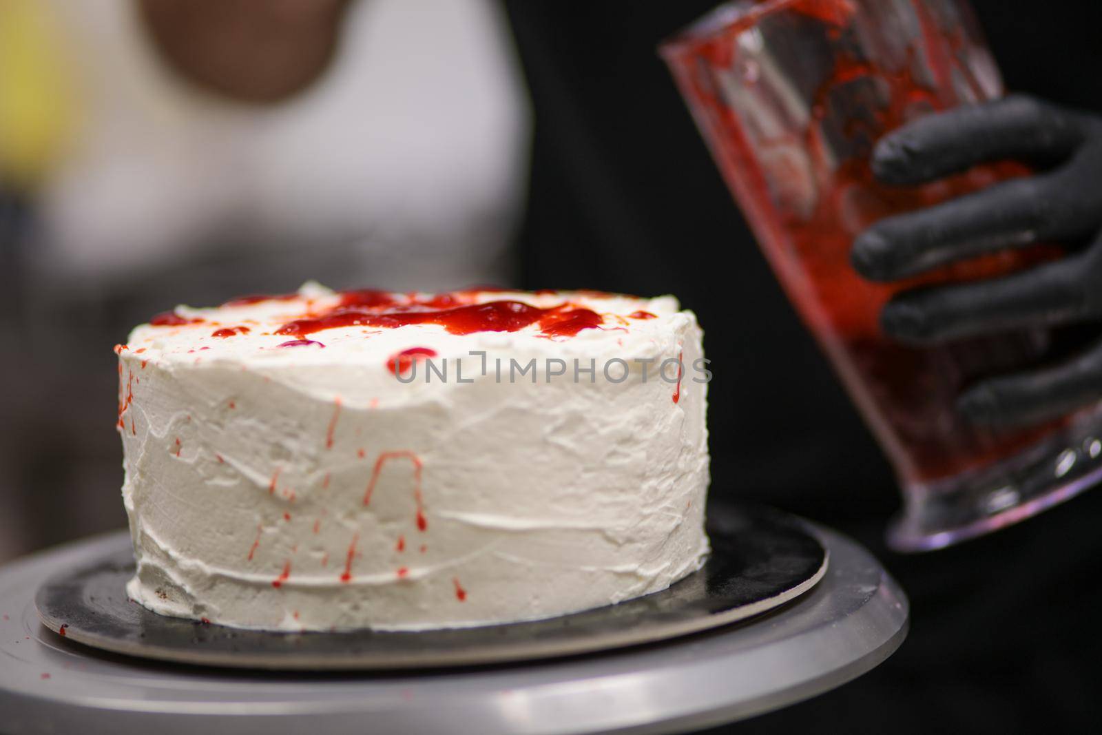 designer chef decorating white red bloody horror crime cake for halloween party by verbano