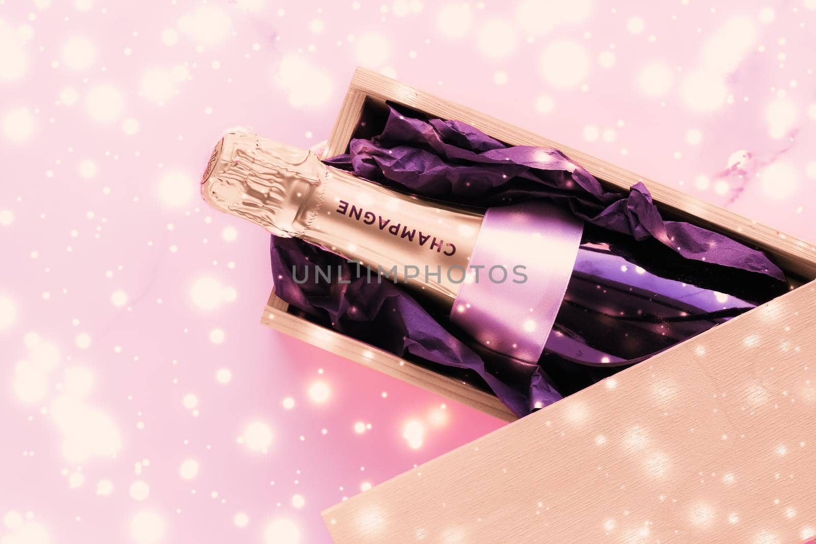 Celebration, drinks and branding concept - Champagne bottle and gift box on pink holiday glitter, New Years, Christmas, Valentines Day, winter present and luxury product packaging for beverage brand