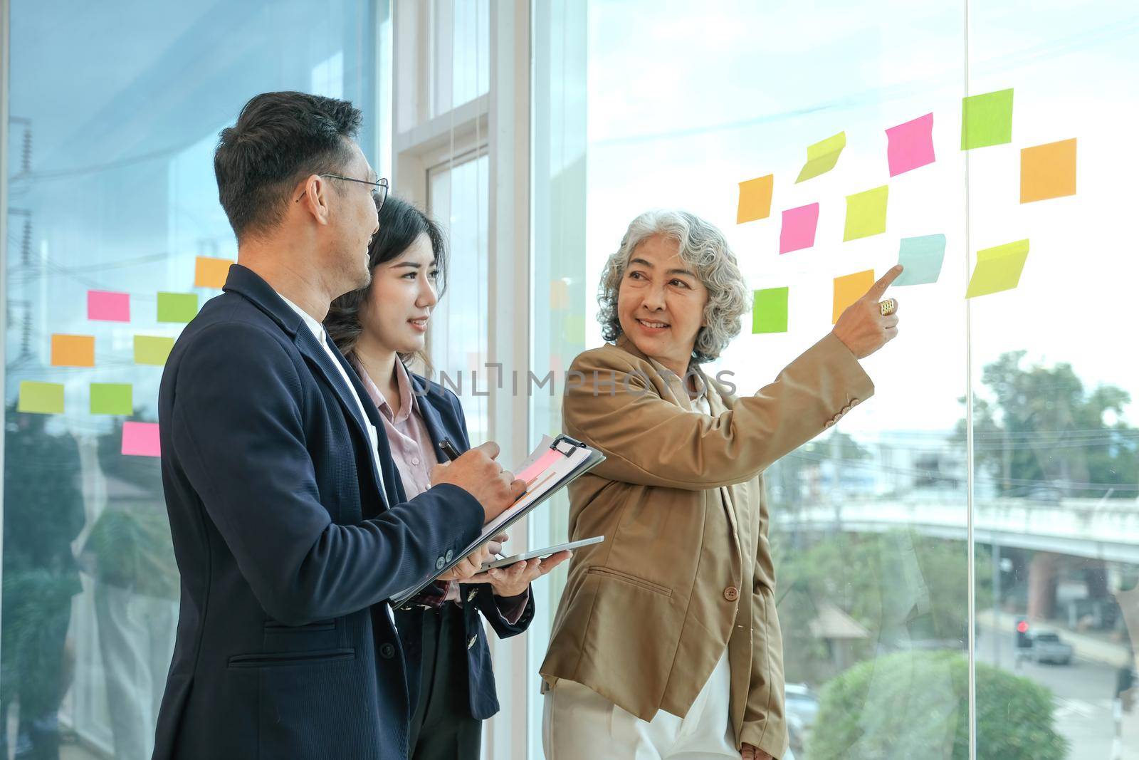 Group of asian young creative happy people entrepreneur on a business meeting office background Good leadership and teamwork lead to success working note ideas with paper note stick by wichayada